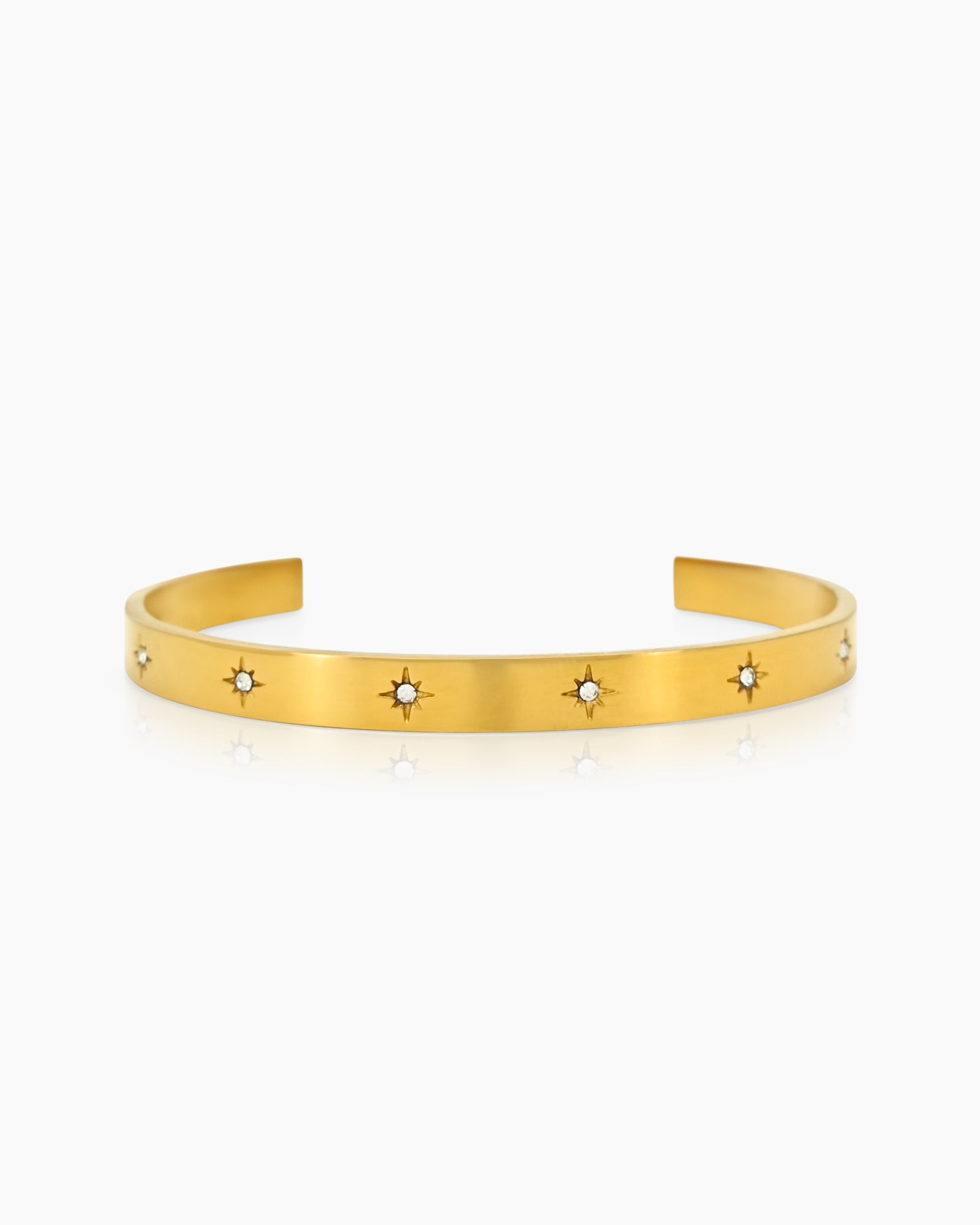 A gold bangle with a smooth, polished finish and tiny star-shaped engravings set with zircon stones