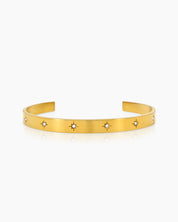 A gold bangle with a smooth, polished finish and tiny star-shaped engravings set with zircon stones