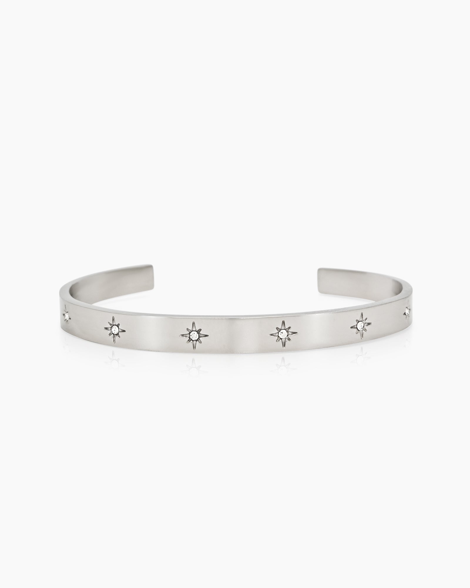 A silver bangle with a smooth, polished finish and tiny star-shaped engravings set with zircon stones