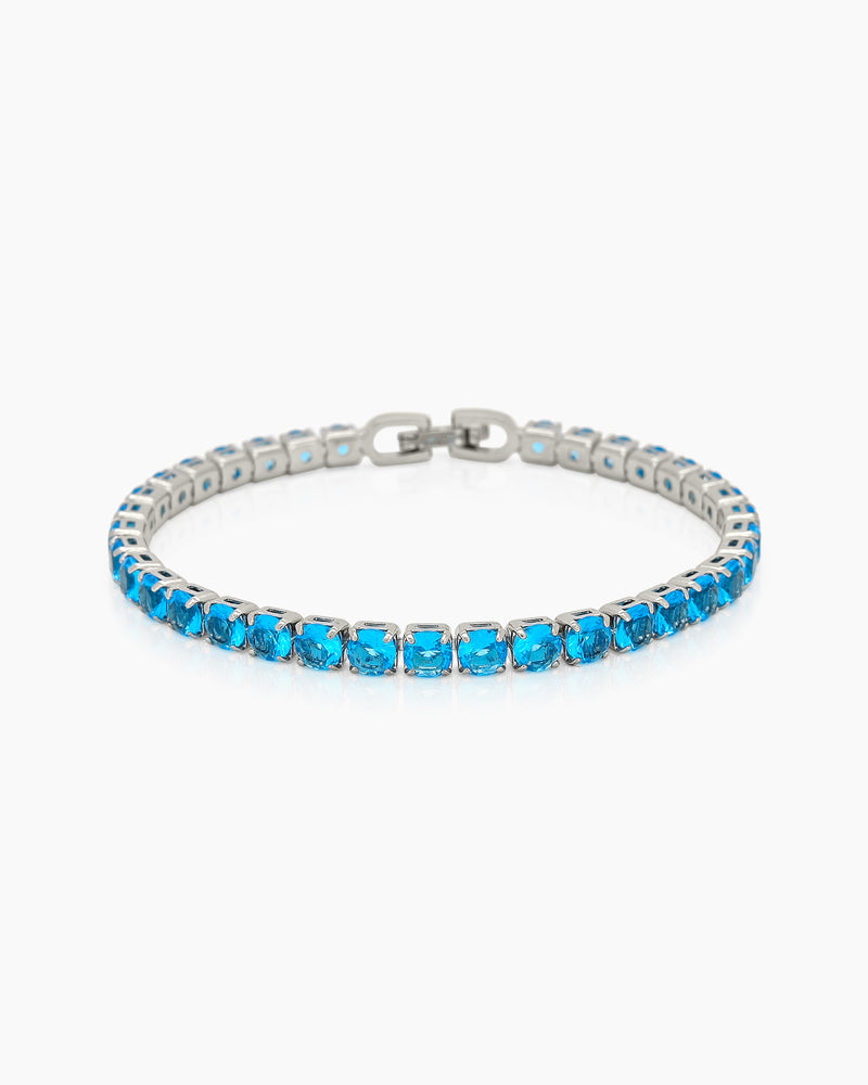 A classic tennis bracelet featuring vibrant, round-cut blue zircon stones in a sleek silver-tone channel