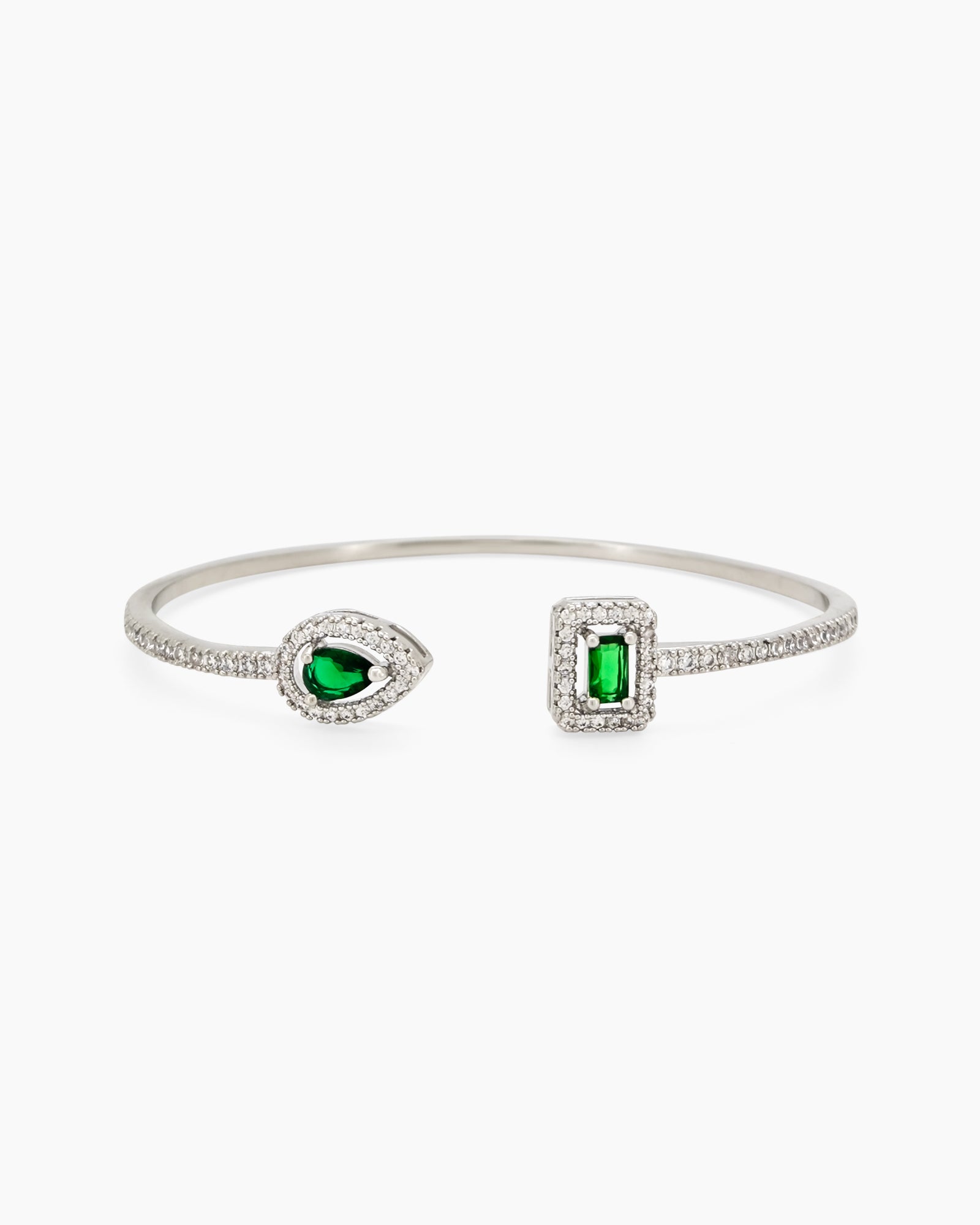 A radiant green open bangle with pear-cut and emerald-cut zircons, each framed by a halo of pavé