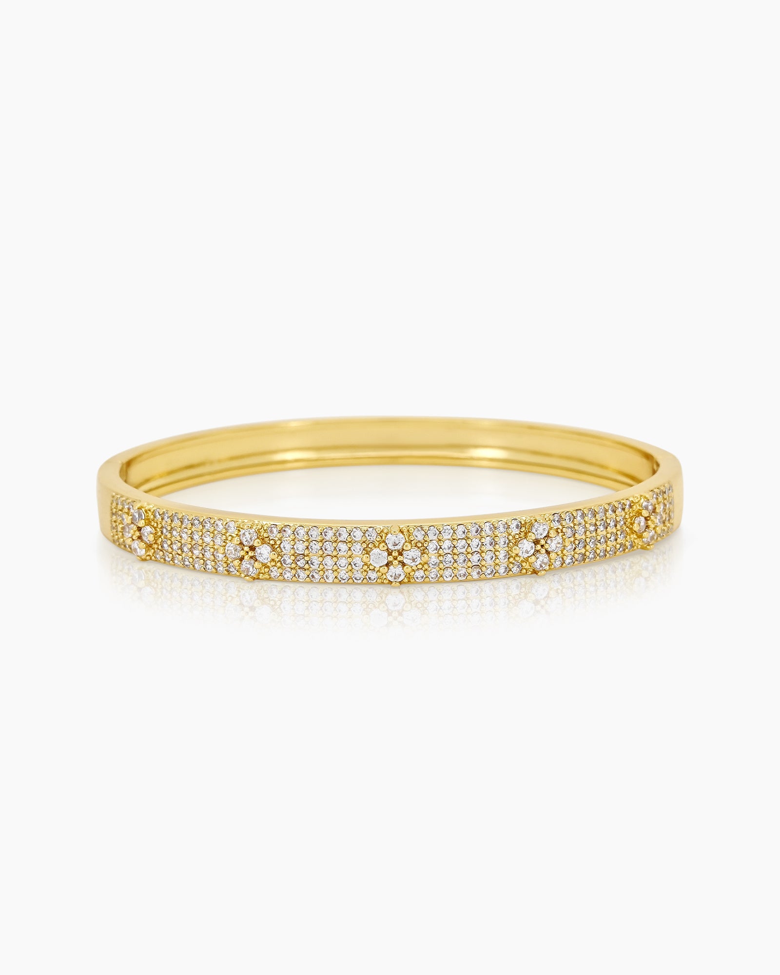 A gold bangle with a sleek silhouette, adorned with pavé-set crystals and brilliant clear zircons