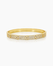 A gold bangle with a sleek silhouette, adorned with pavé-set crystals and brilliant clear zircons