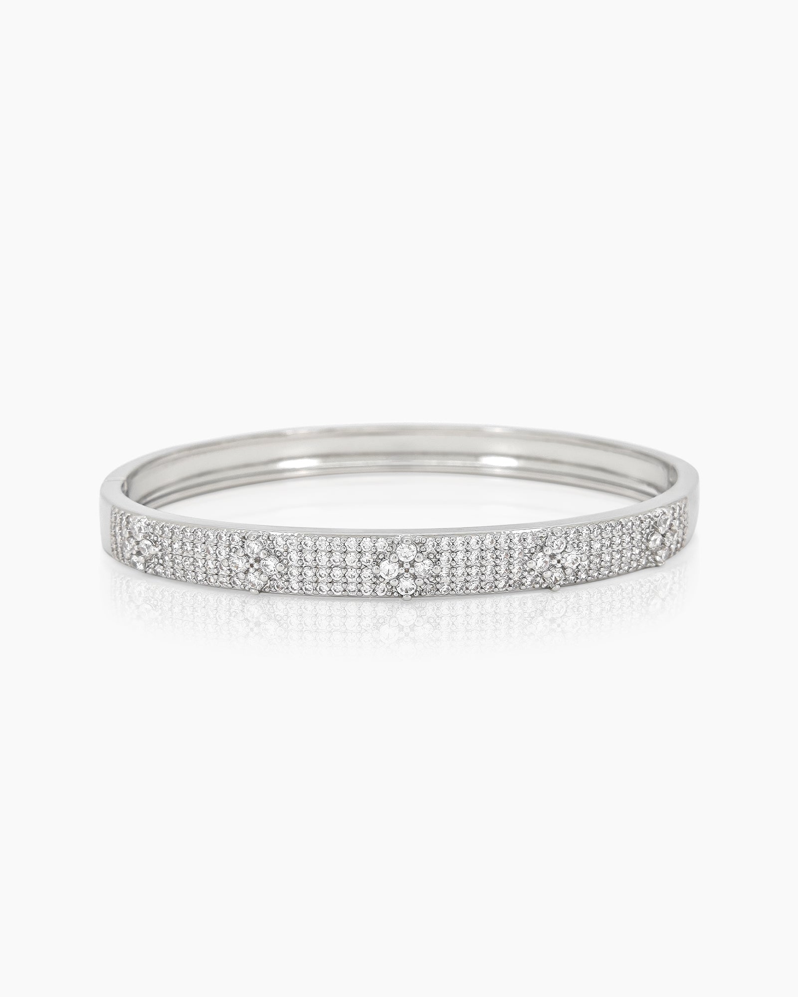 A silver bangle with a sleek silhouette, adorned with pavé-set crystals and brilliant clear zircons