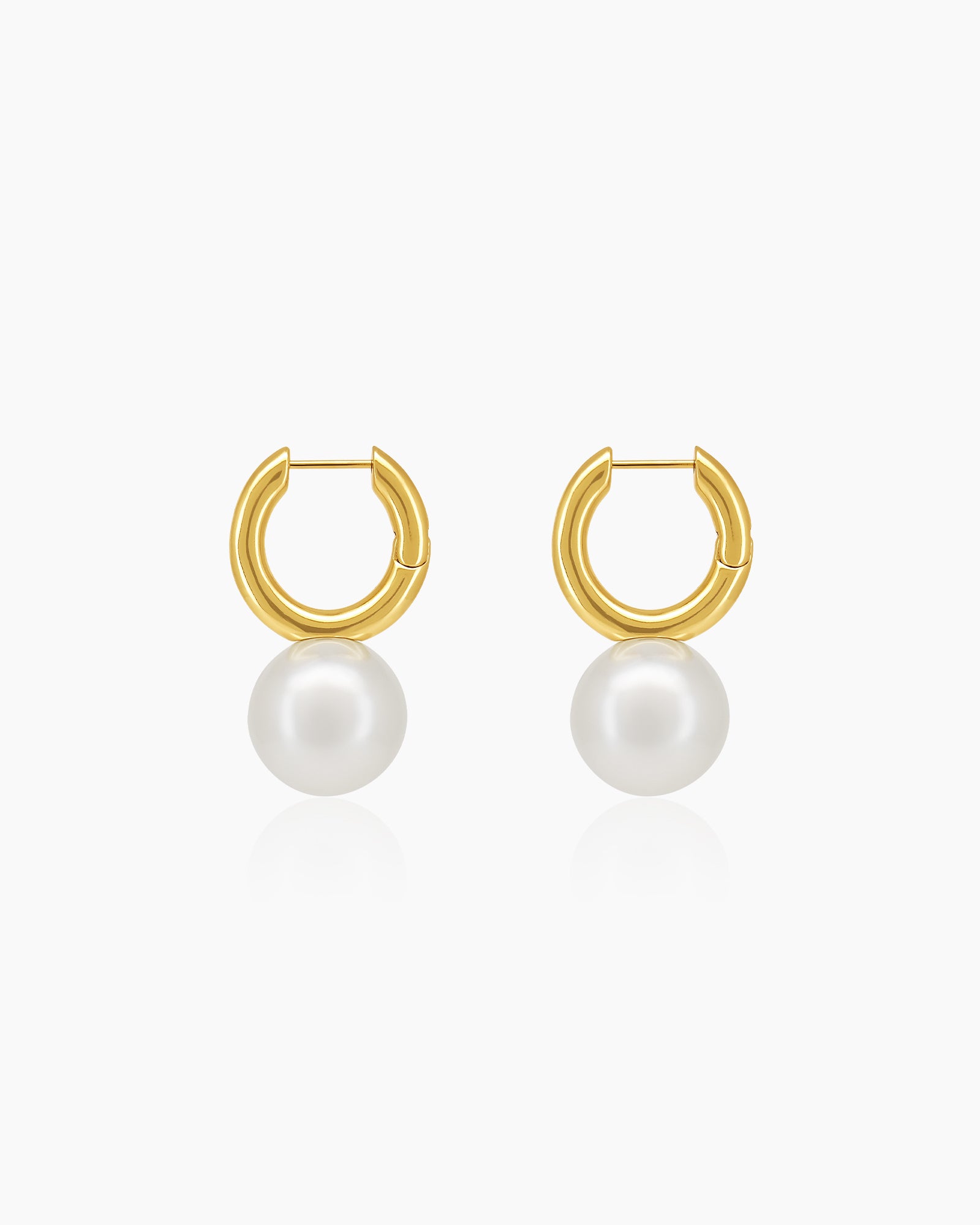 Thick, polished gold huggie earrings with a smooth, spherical drop for a sculptural touch
