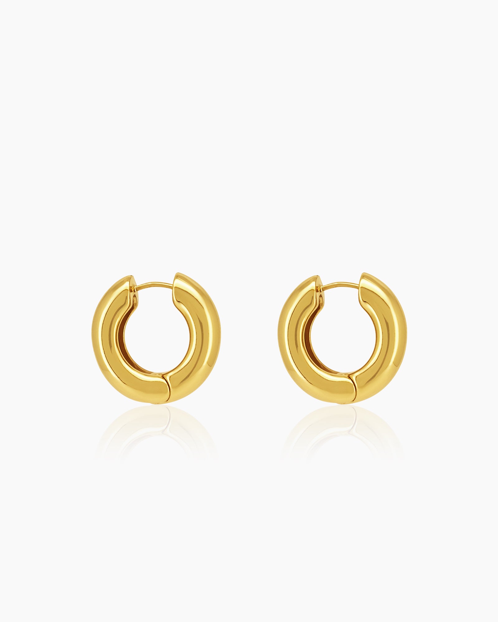 Chunky gold hoop earrings sculpted into a perfect round with a smooth surface that catches the light