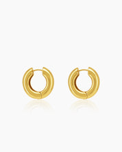 Chunky gold hoop earrings sculpted into a perfect round with a smooth surface that catches the light