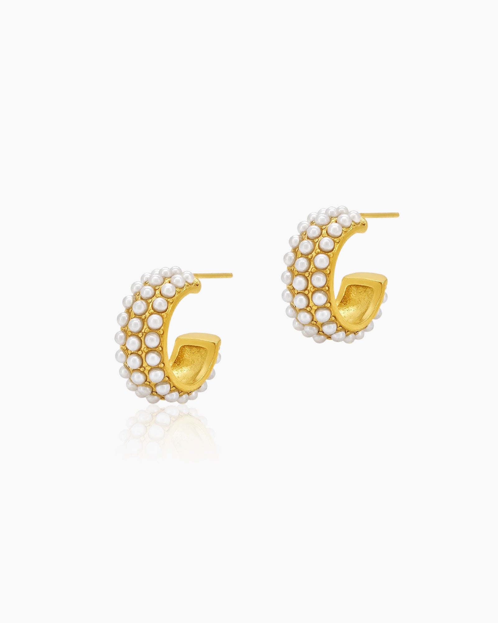 Modern huggie hoop earrings with three rows of delicate faux pearls set on a glossy gold-tone base