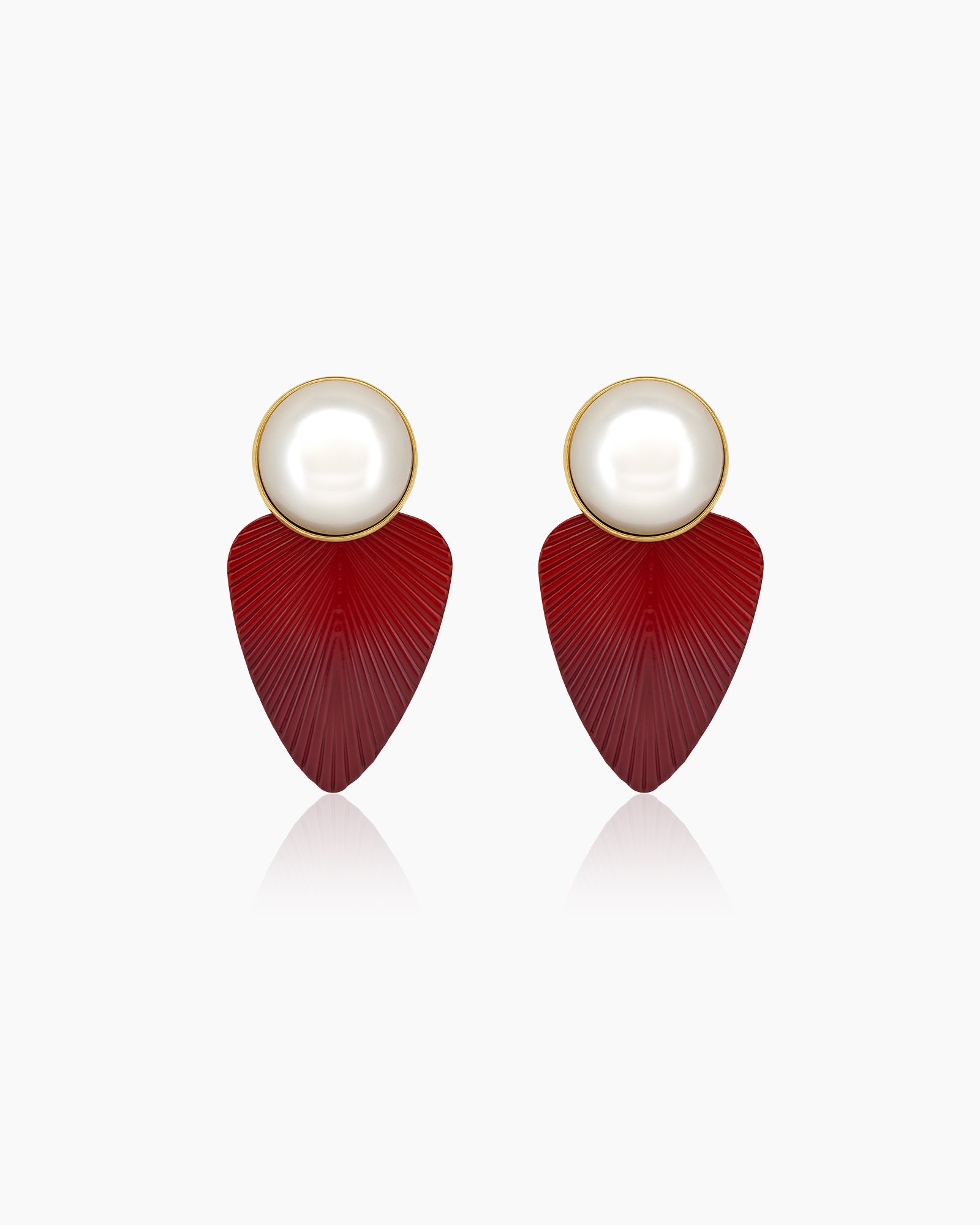 Statement earrings with oversized faux pearls and glossy, deep red leaf-shaped drops with etched textures