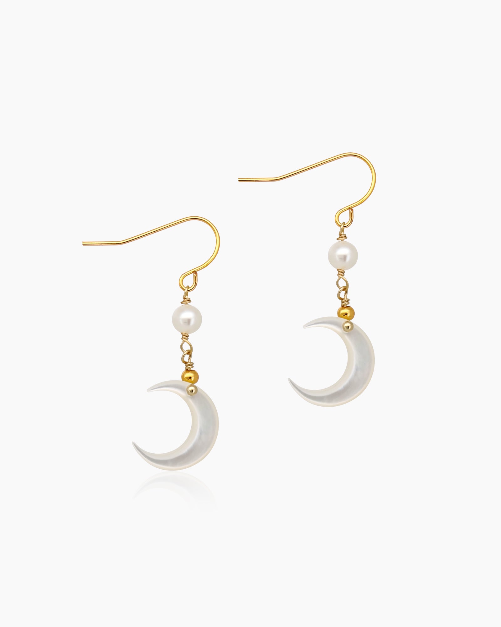 Earrings with an iridescent mother-of-pearl crescent moon suspended beneath a dainty pearl accent