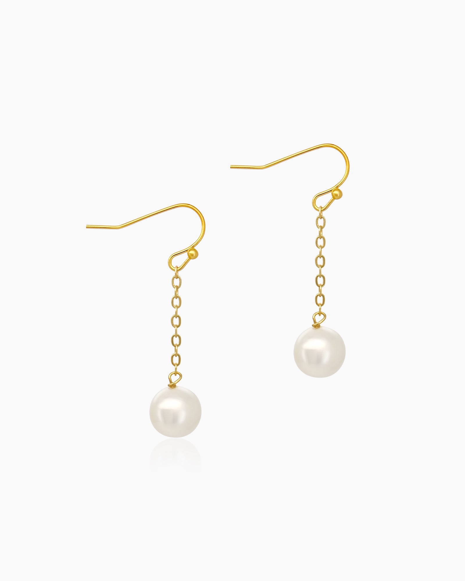 Earrings with delicate gold-toned chains from which luminous pearls dangle like drops of moonlight