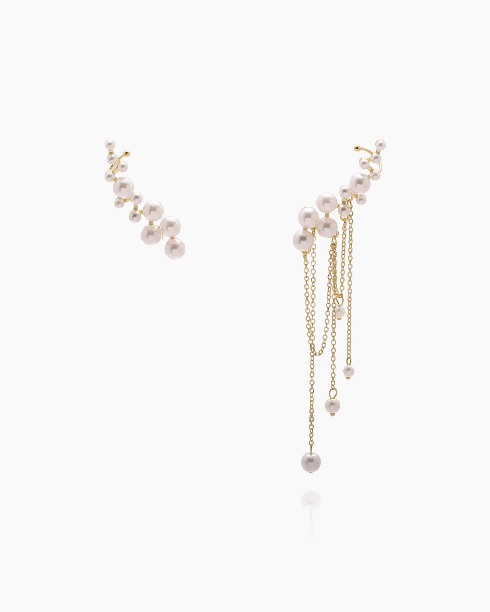 An asymmetric ear cuff and earring set with sculptural clusters of faux pearls and cascading gold chains