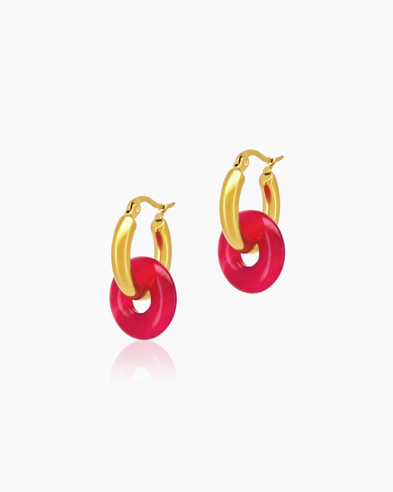 Chunky gold-toned huggie hoops featuring fuchsia natural carnelian donut charms for a playful look