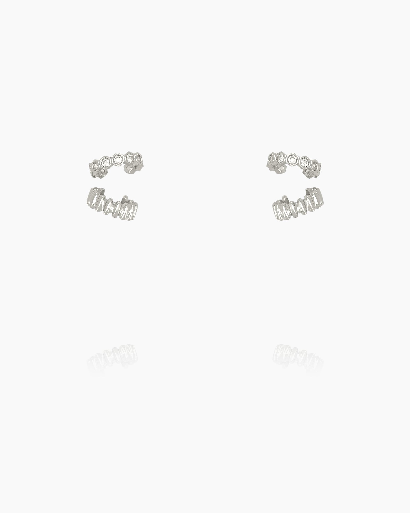 A set of ear cuffs, one with polished metallic ridges and another with radiant hexagon-cut zircons