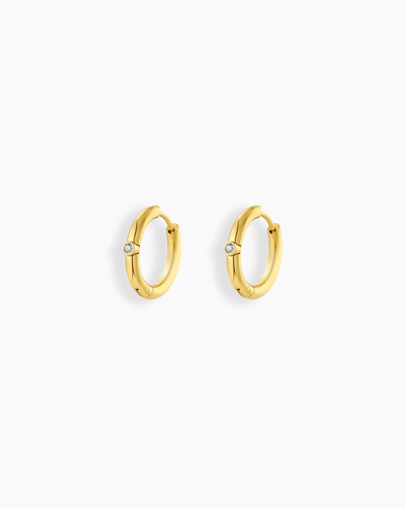 Huggie earrings with a smooth gold-tone finish and a single cubic zirconia stone on each hoop