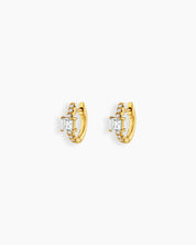 White huggie earrings with a sleek gold-tone hoop, a baguette-cut center stone, and a delicate arc of pavé