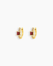 Red huggie earrings with a sleek gold-tone hoop, a baguette-cut center stone, and a delicate arc of pavé