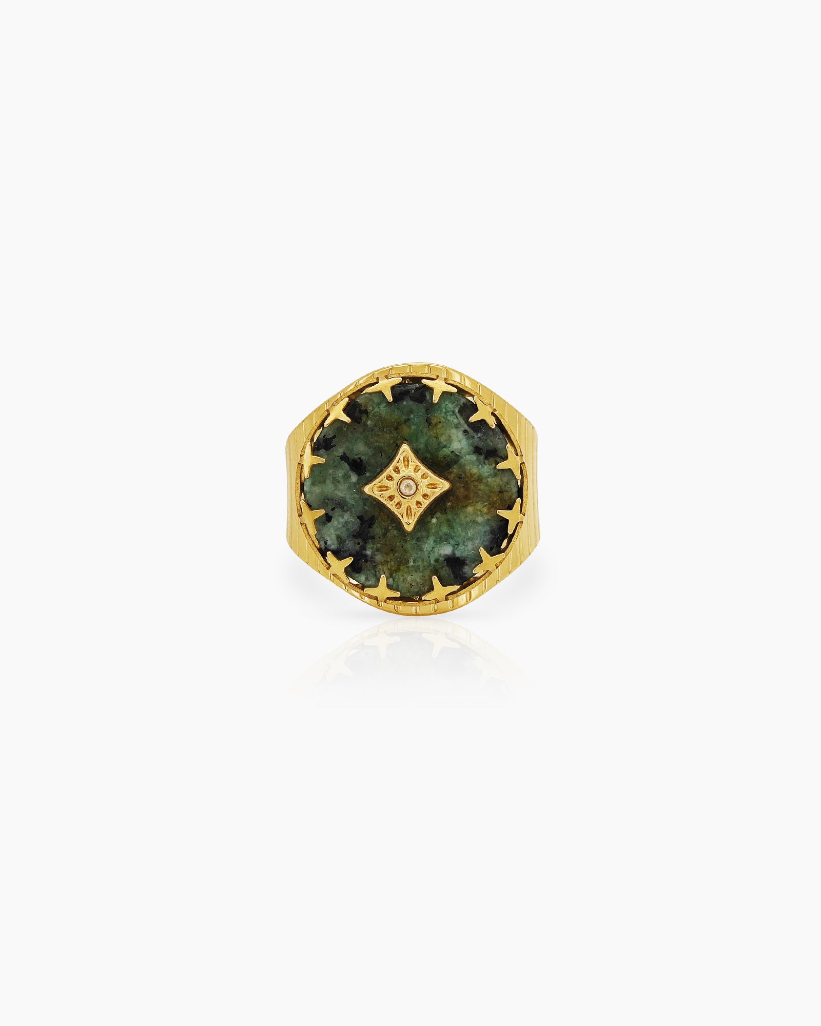 An adjustable ring with a textured gold band and a green african pine center stone, crowned by a crystal