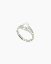 A silver ring with a fluid, sculptural band and a luminous pearl for a modern, poetic look