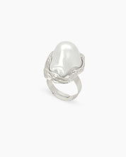 A sculptural silver ring with graceful curves and an oversized faux pearl in a textured frame