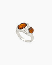 A silver vintage ring with amber-hued rhinestones and an intricately molded, molten-texture band