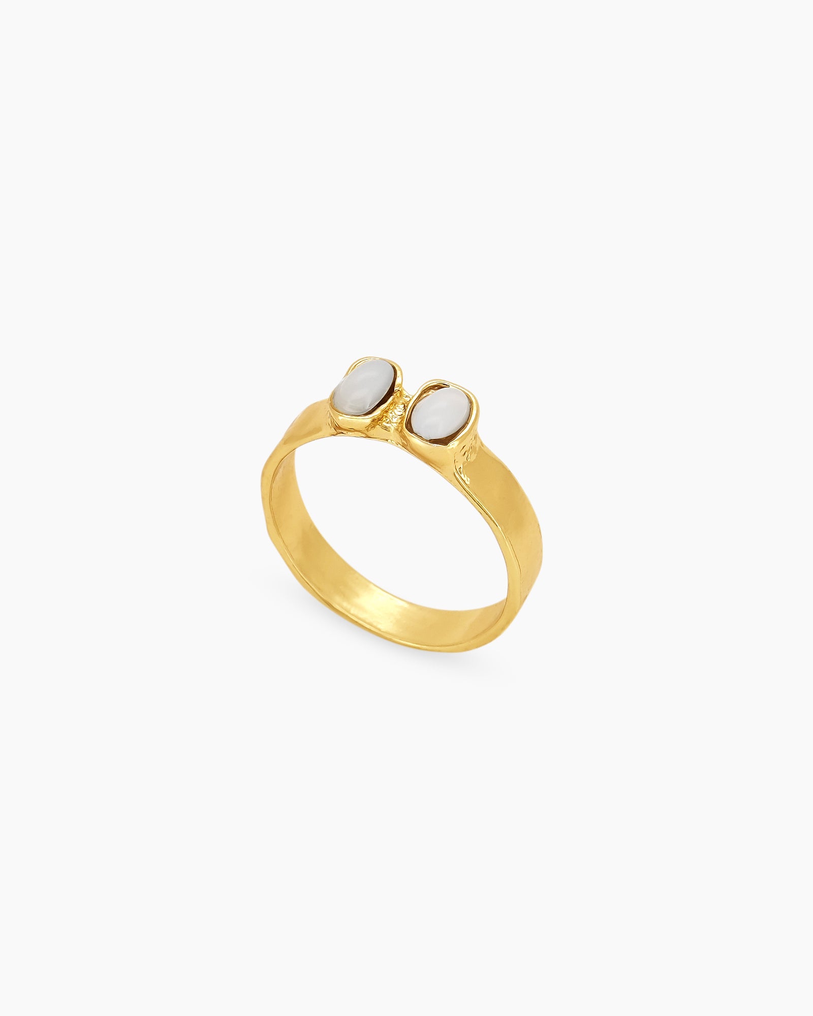 A gold vintage-style ring with two milky rhinestones nestled into a gently hammered band