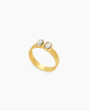 A gold vintage-style ring with two milky rhinestones nestled into a gently hammered band