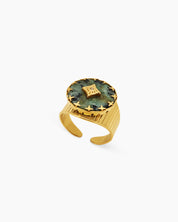 An adjustable ring with a textured gold band and a green african pine center stone, crowned by a crystal