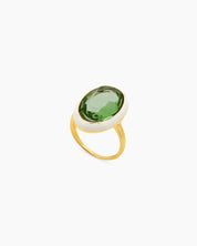 A green-white cocktail ring with a large, faceted oval stone framed by a glossy enamel halo on a gold band
