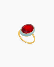 A red-blue cocktail ring with a large, faceted oval stone framed by a glossy enamel halo on a gold band
