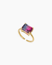 A blue-to-rose-red ring with an emerald-cut ombré zircon that shifts in the light, on a sleek open band