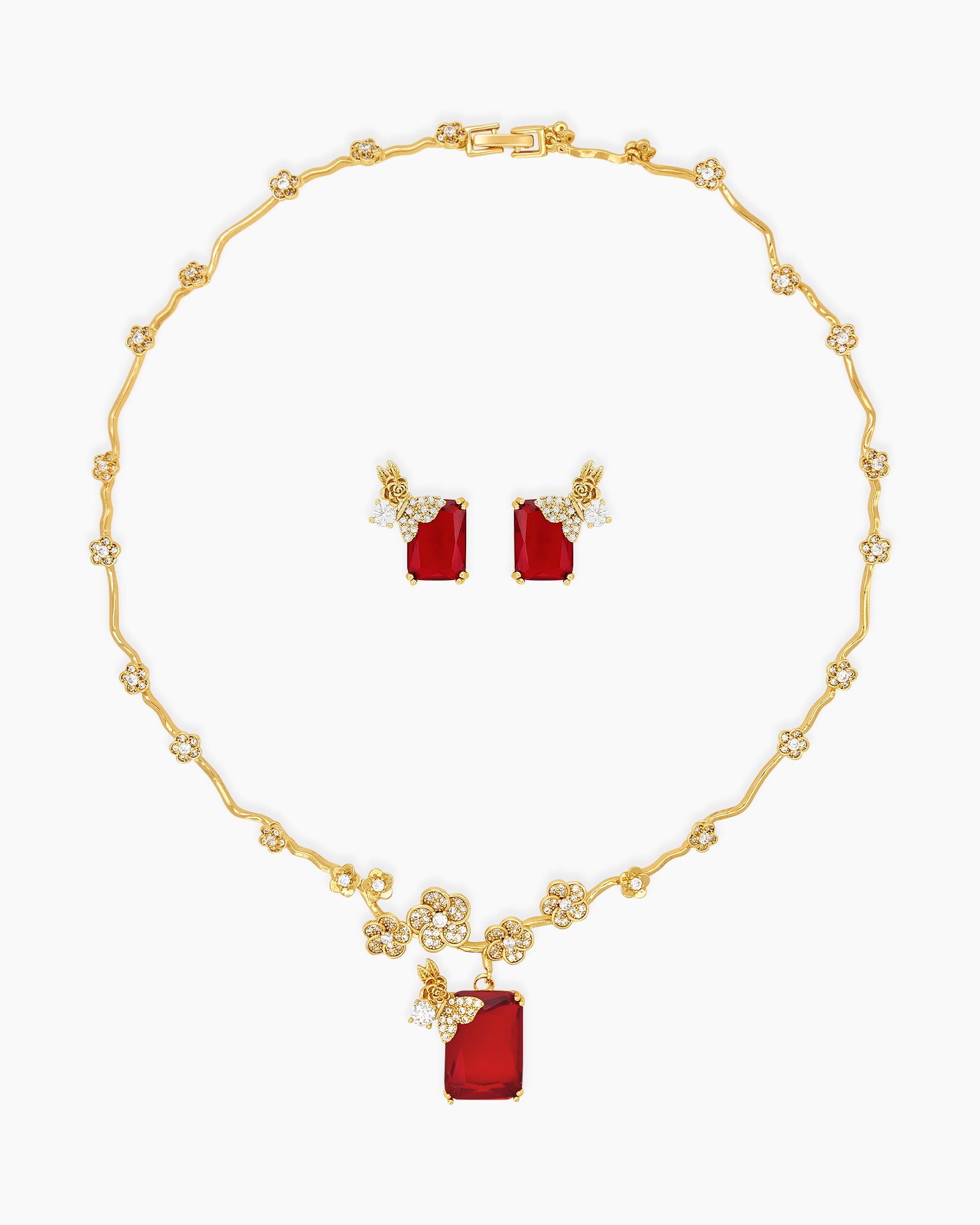 A jewelry set with gold-toned floral links, fine zircons, and a striking, deep crimson emerald-cut stone
