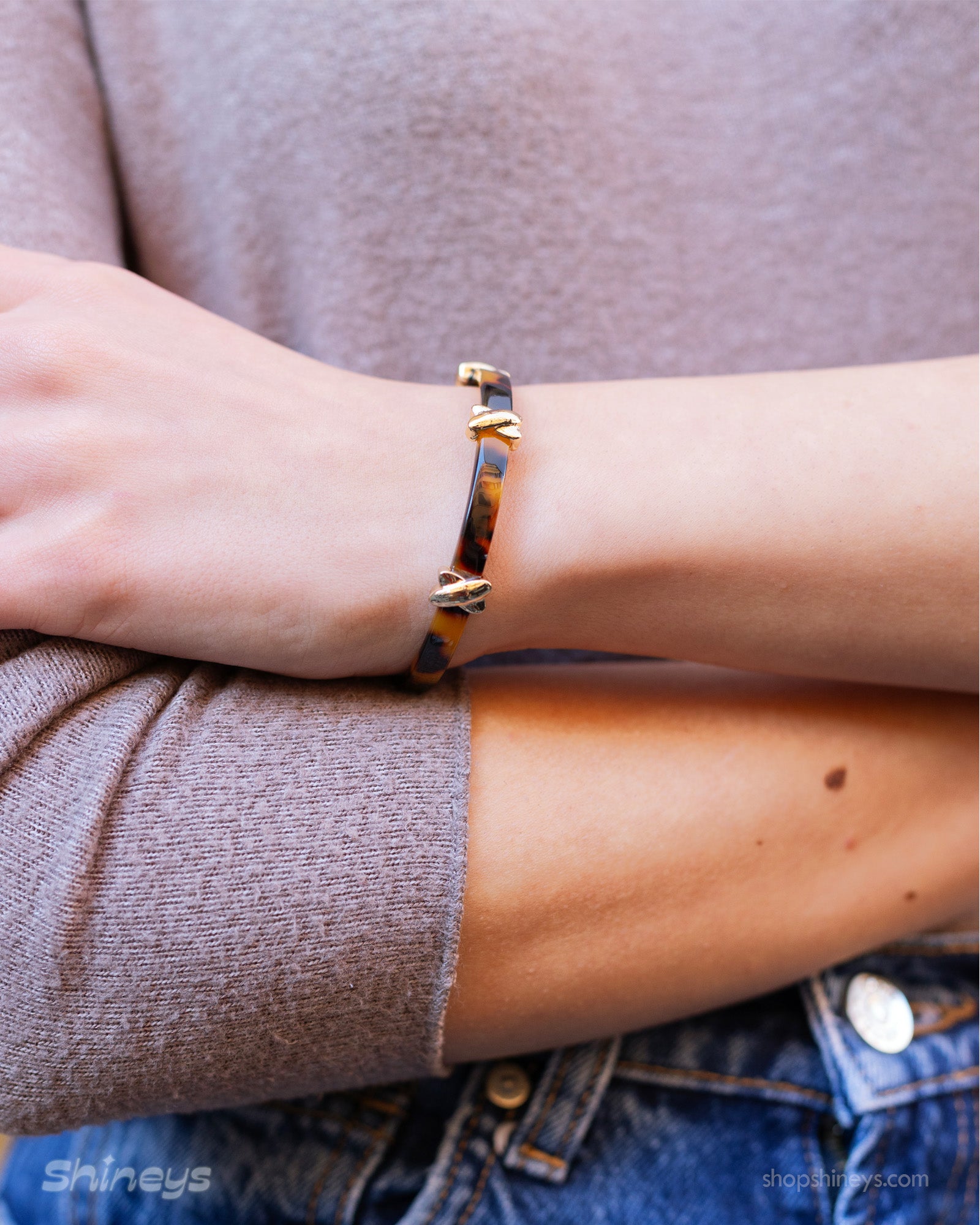 A double-wrapped bangle in high-gloss acrylic with a tortoiseshell effect and polished cross details