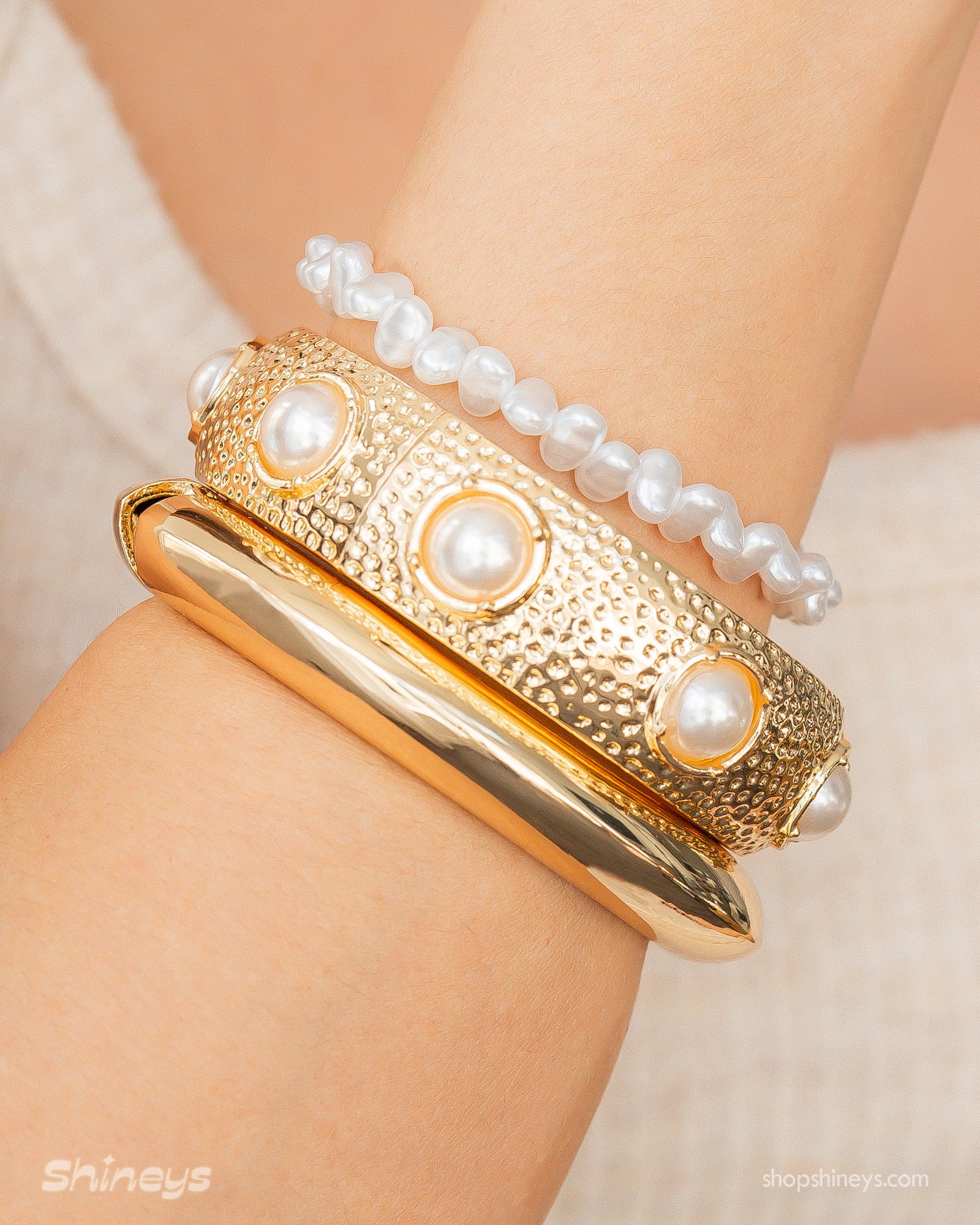 A set of three bracelets: Astoria Minimalist Bangle, Nausicaa Pearl Bangle, and Haya White Bracelet