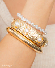 A set of three bracelets: Astoria Minimalist Bangle, Nausicaa Pearl Bangle, and Haya White Bracelet