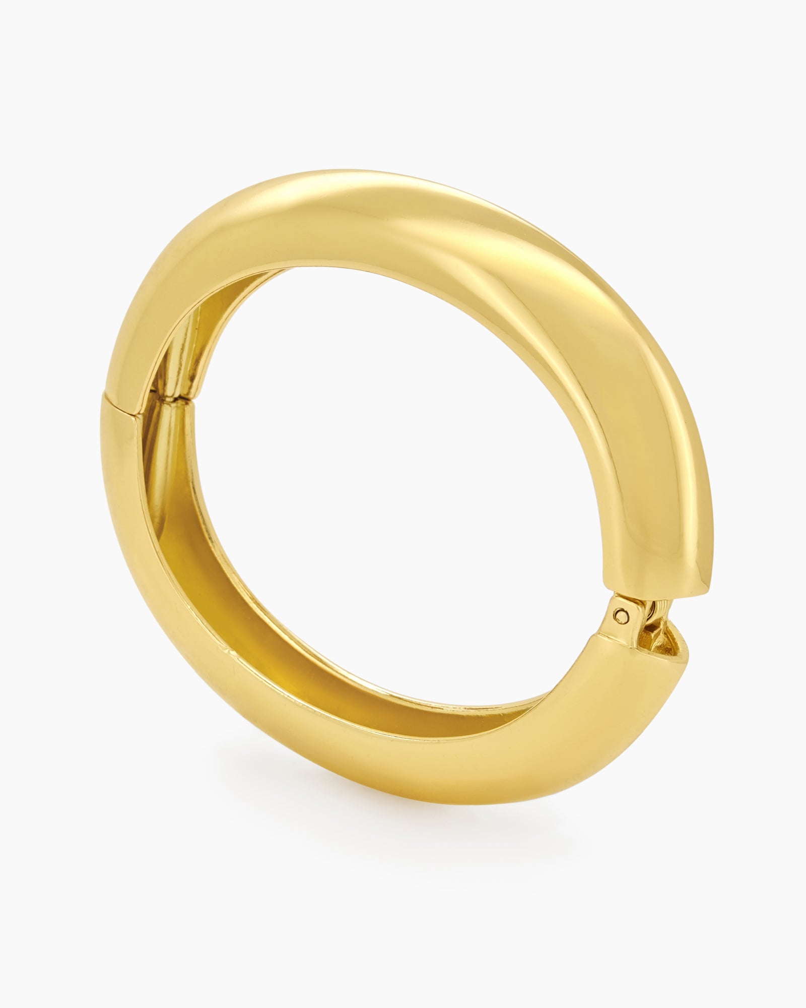 A sculptural gold bangle with a bold, rounded silhouette, high-polish finish, and seamless hinge closure