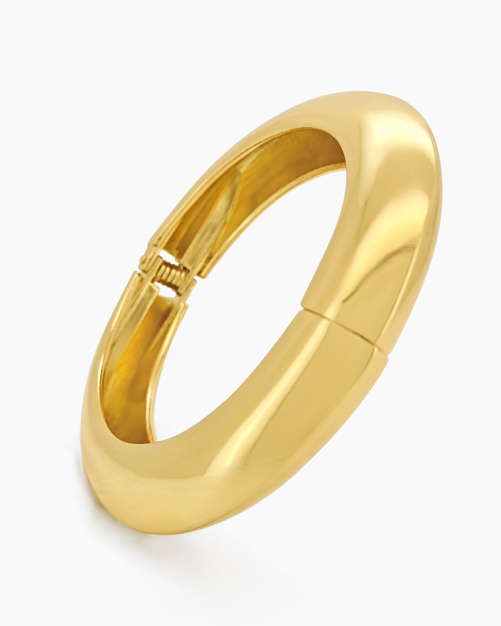 A sculptural gold bangle with a bold, rounded silhouette, high-polish finish, and seamless hinge closure