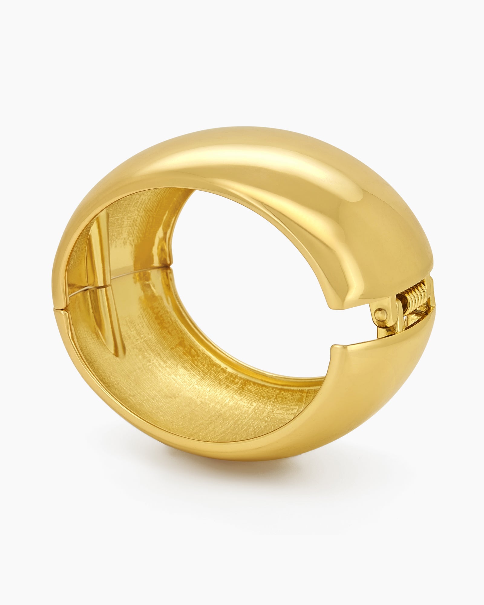 A gold bangle with a wide, mirror-like surface and a curved silhouette for a sleek, modern look