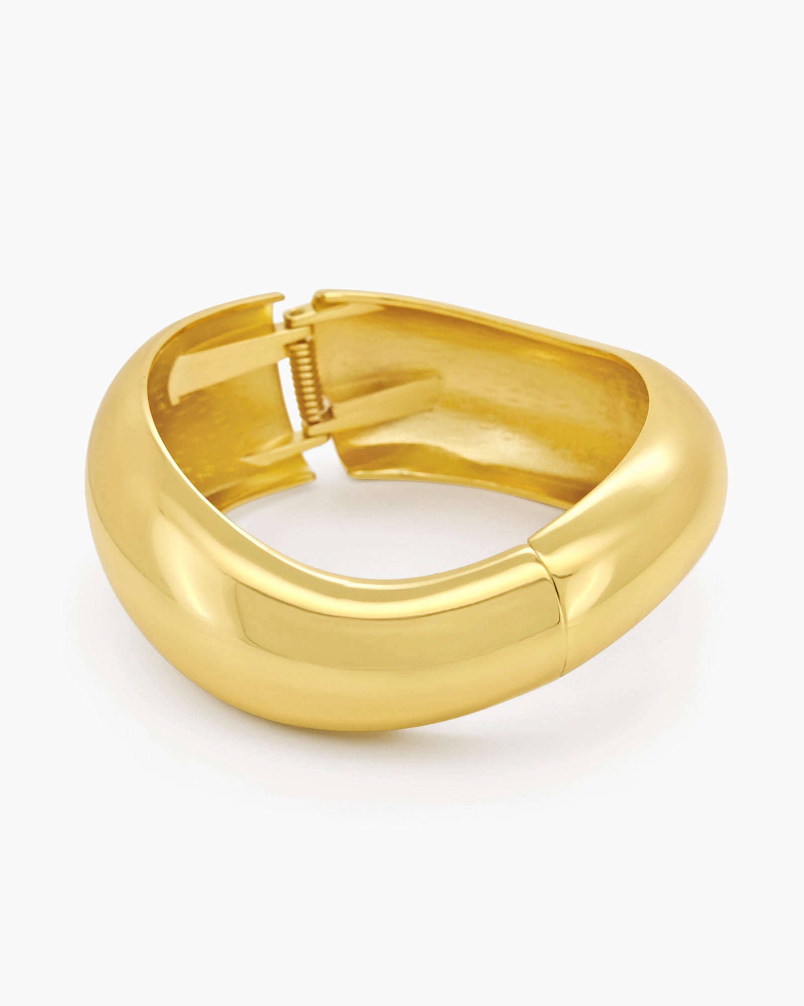 A gold hinged bangle with smooth curves and a fluid, wave-like silhouette for a minimalist focus