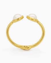 A polished gold cuff with two oversized faux pearls in a glossy frame and a secure hinge closure