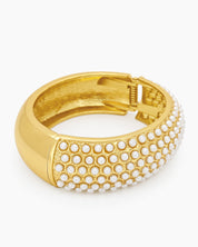 A gold-tone bangle encrusted with rows of tiny faux pearls, creating a soft, sculptural rhythm