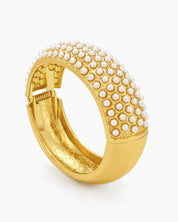 A gold-tone bangle encrusted with rows of tiny faux pearls, creating a soft, sculptural rhythm