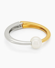 A mixed-metal hinged bangle pairing silver and gold in a seamless line, with a single pearl accent