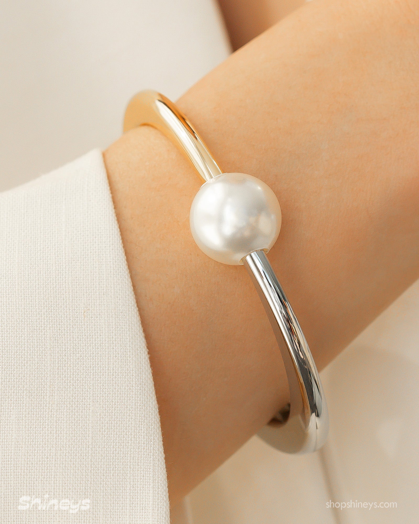 A mixed-metal hinged bangle pairing silver and gold in a seamless line, with a single pearl accent
