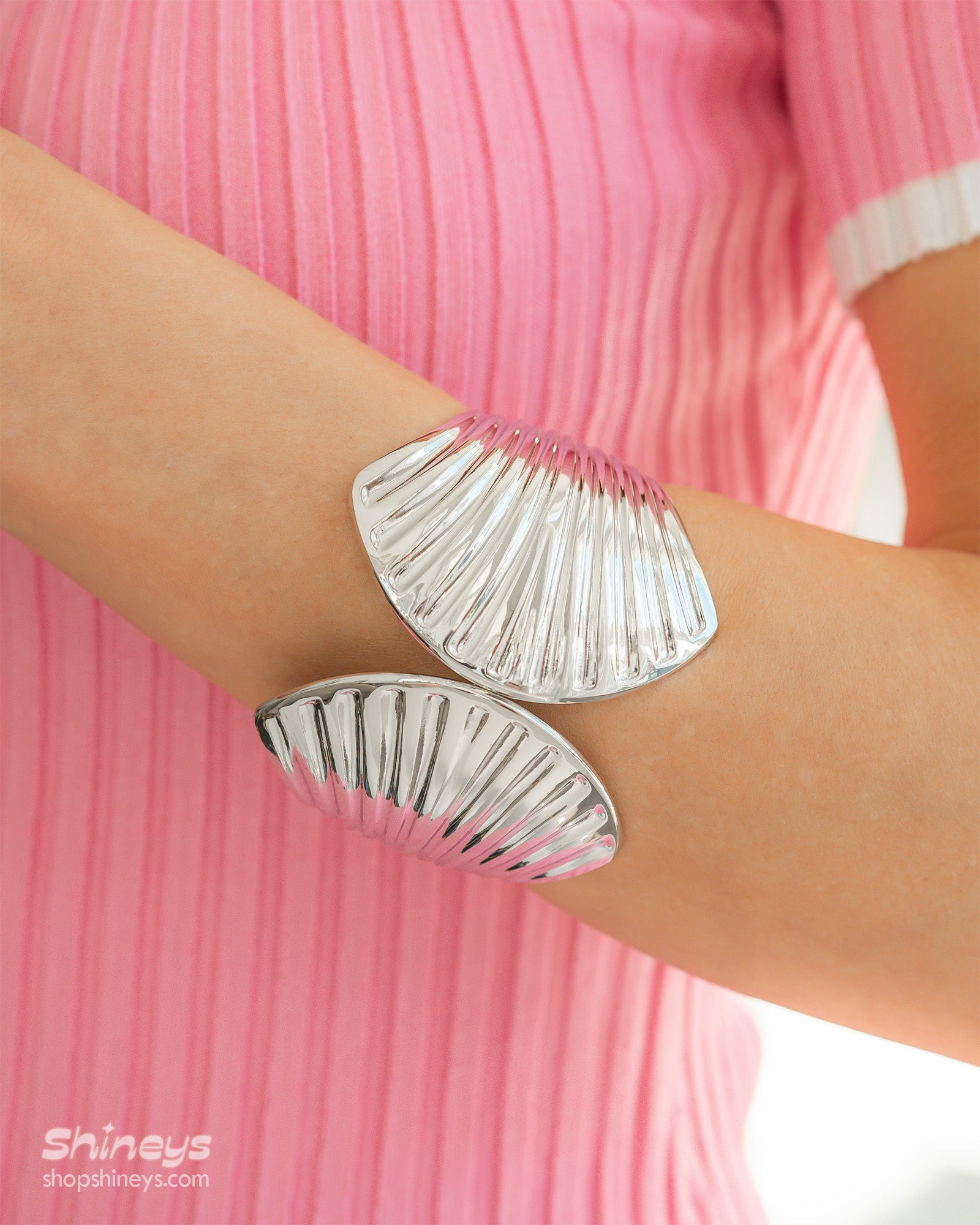 A polished silver hinged bangle sculpted with flowing, shell-inspired ridges for a bold, statement look