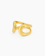 A gold open ring with a thick, smooth, and reflective curve that creates a fluid, playful presence