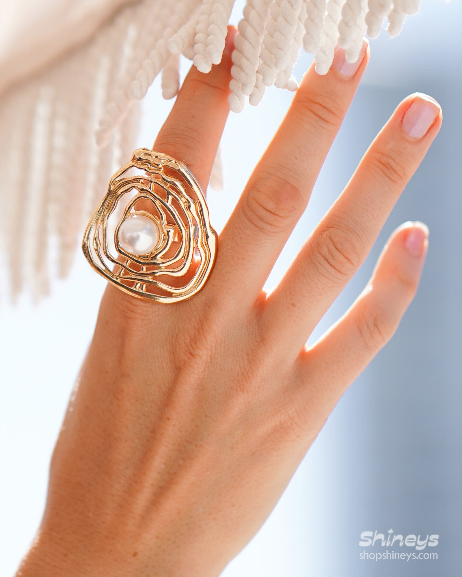 A sculptural gold ring with an abstract shell design cradling a luminous faux pearl