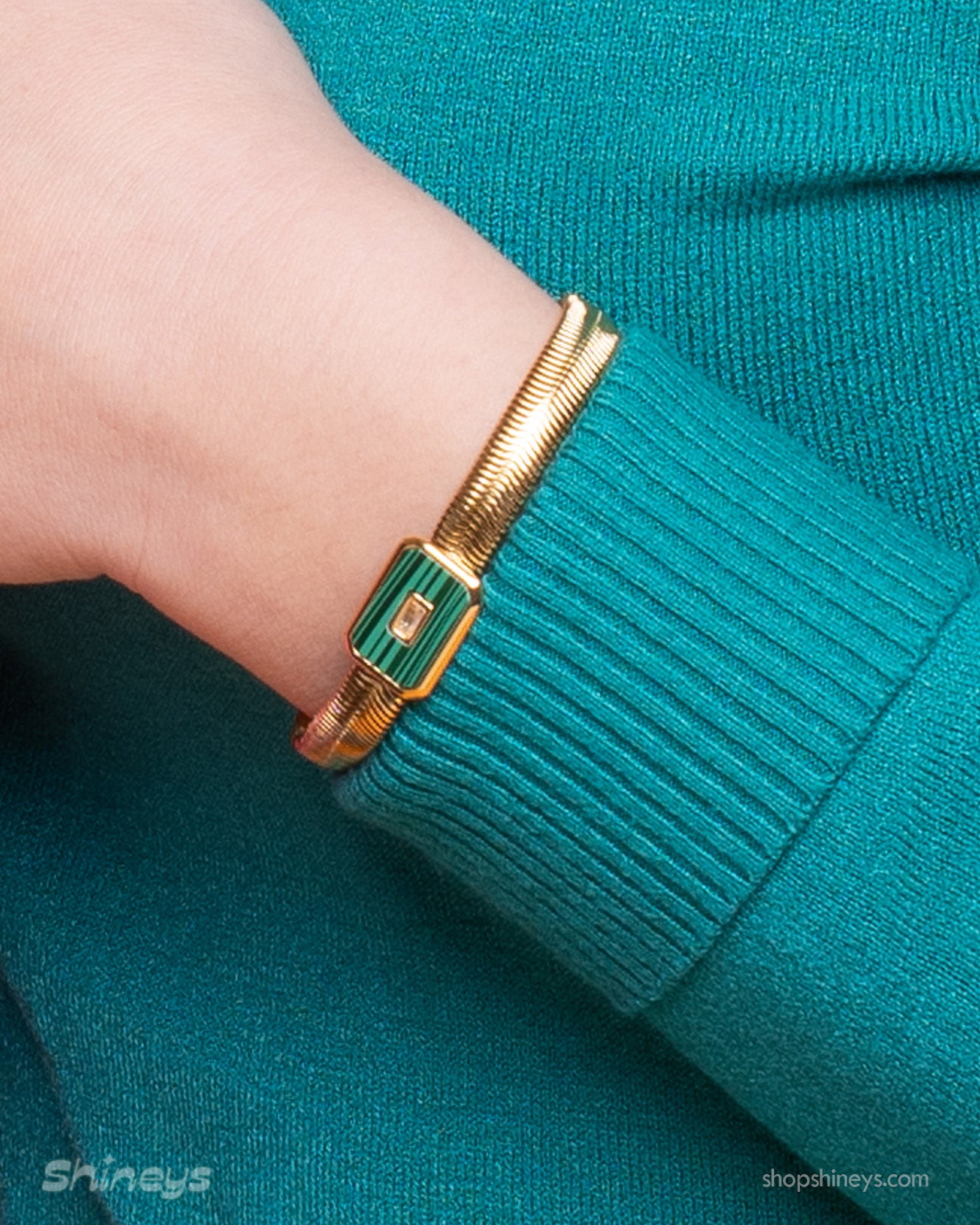 A green bracelet with a bold gold-tone snake chain and a rectangular malachite charm