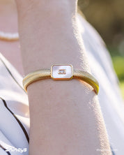 A white bracelet with a bold gold-tone snake chain and a rectangular mother-of-pearl charm