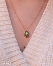 A necklace with a green african pine stone pendant in a textured gold-toned bezel with a diamond motif
